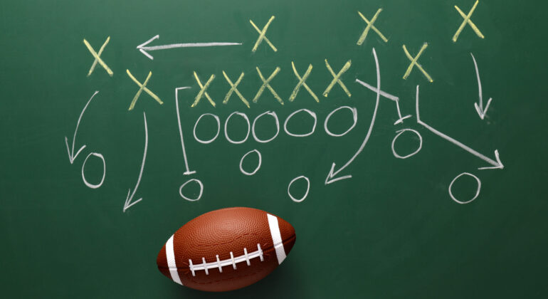 Rugby ball and scheme of football game drawn on chalkboard